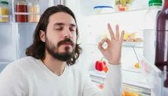 Muž před otevřenou lednicí ukazuje gesto OK, spokojenost s výběrem jídla.