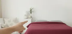 Minimalistická ložnice s červenou dekou, bílou stěnou a ukazující rukou